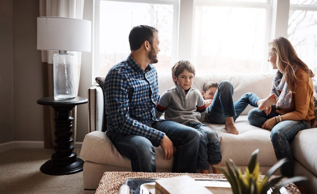 Family sits together on a couch during an in-home counseling session.