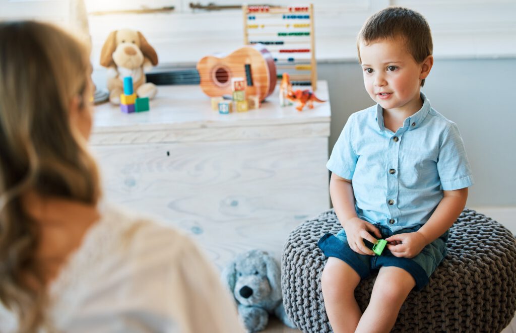 Young boy in therapy session with counselor in a playroom