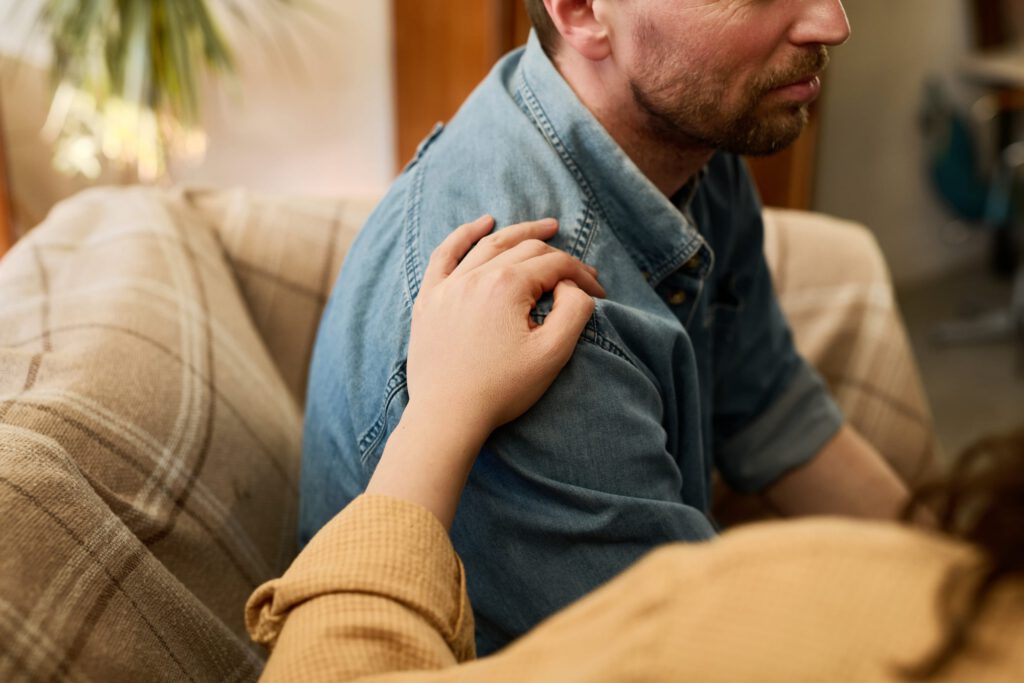Supportive hand on a man's shoulder offering comfort