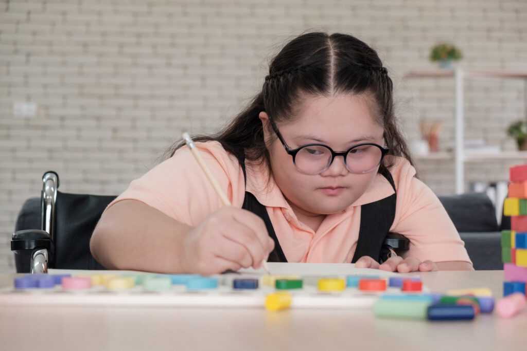 Child using paint to create art at a table in an inclusive activity setting