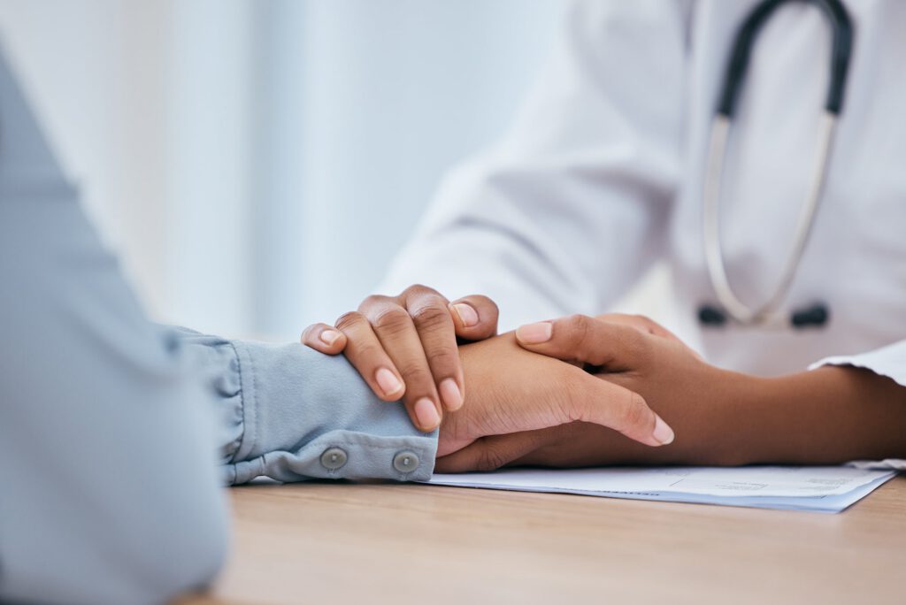 Healthcare provider holding a patients hand with compassion during a medication assisted treatment consultation