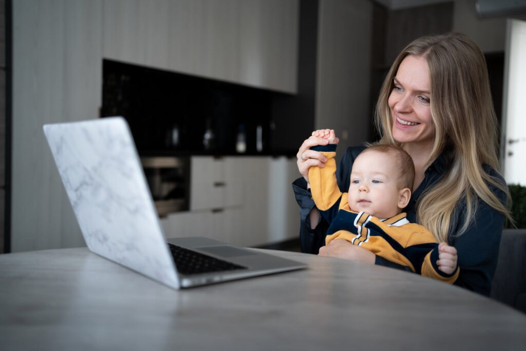 Mother and baby waving during a video call on a laptop