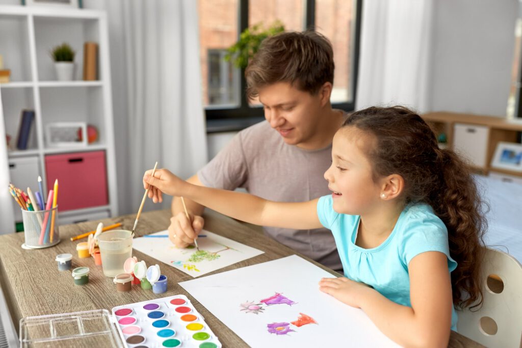 Parent and child painting together at a table with art supplies