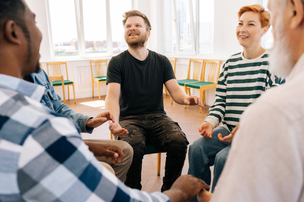 Diverse group of adults participating in a peer support group therapy session