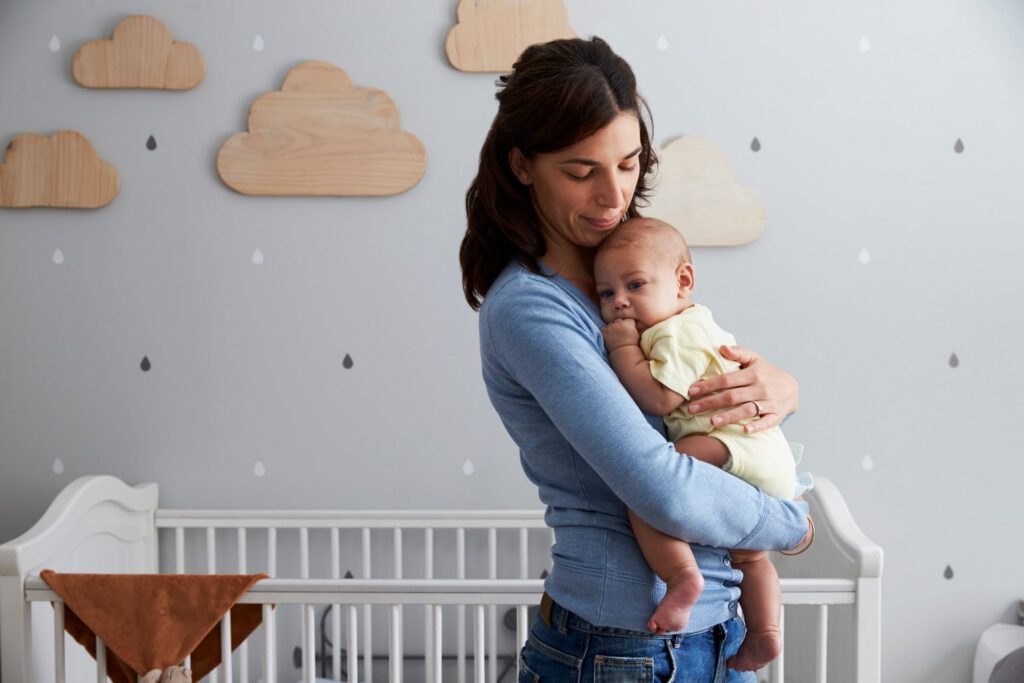 Mother comforting and holding her baby in a nurturing nursery setting at a womens recovery center