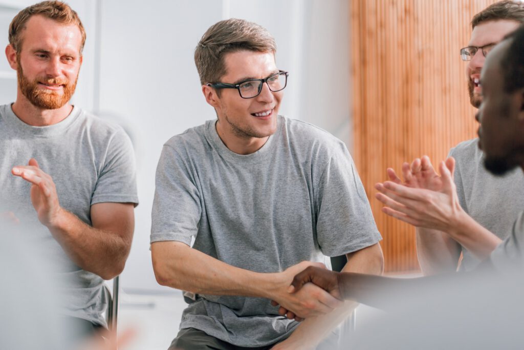Men shaking hands and supporting each other during a group therapy session at a residential treatment center