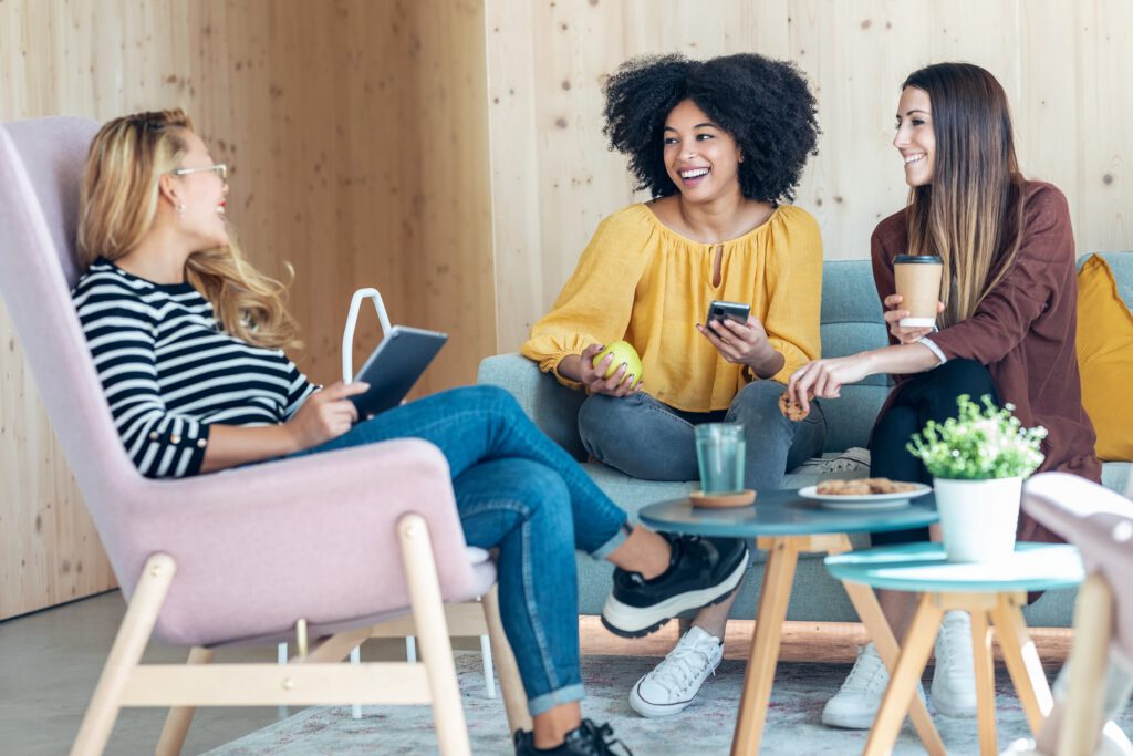 Three women talking and smiling together in a casual support setting
